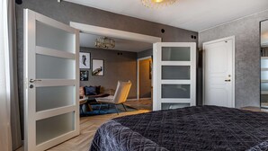 A bedroom with a large bed, a chair, and a wardrobe with frosted glass doors.