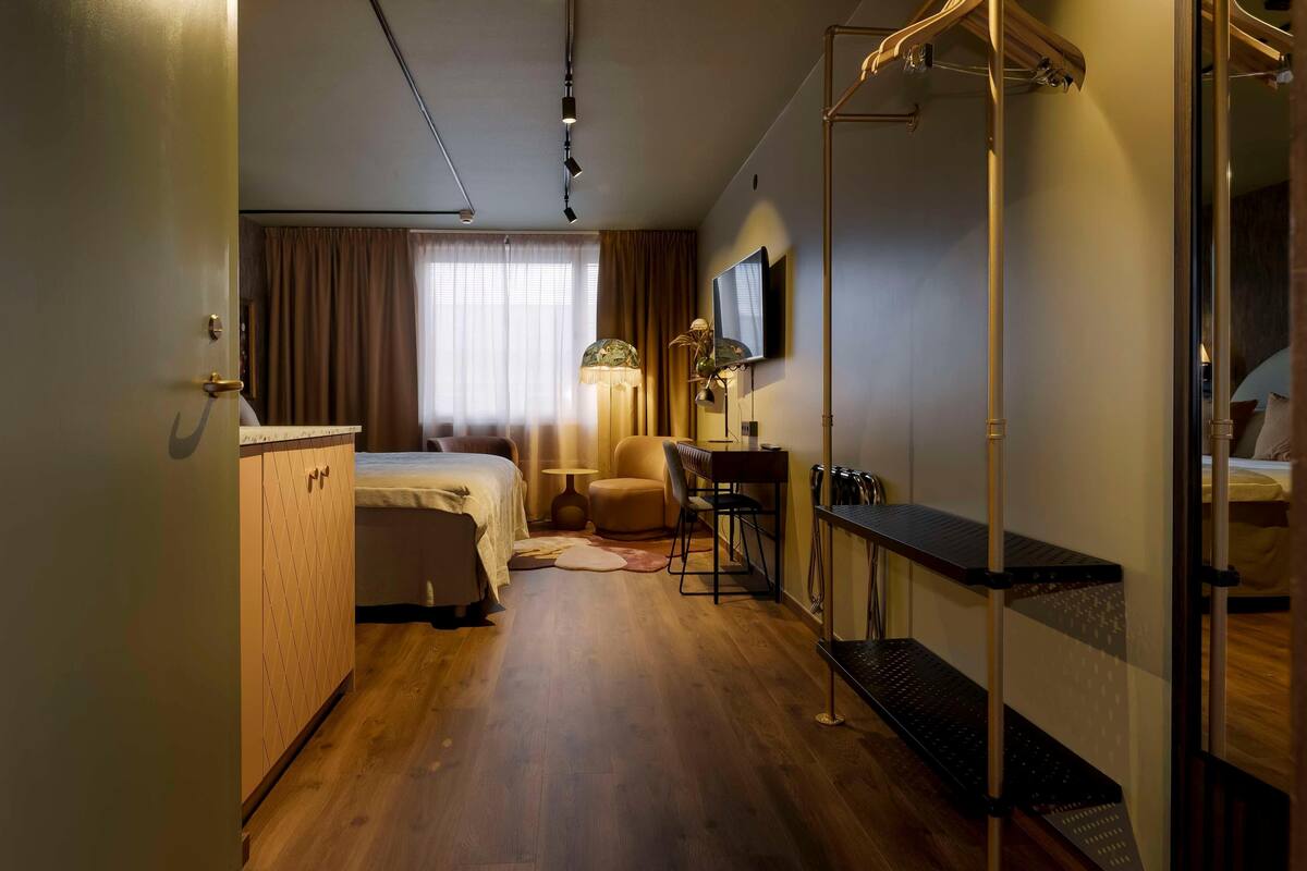 Une chambre d’hôtel équipée d’un lit, d’un bureau, d’une chaise, d’une lampe, d’une télévision et d’une armoire.