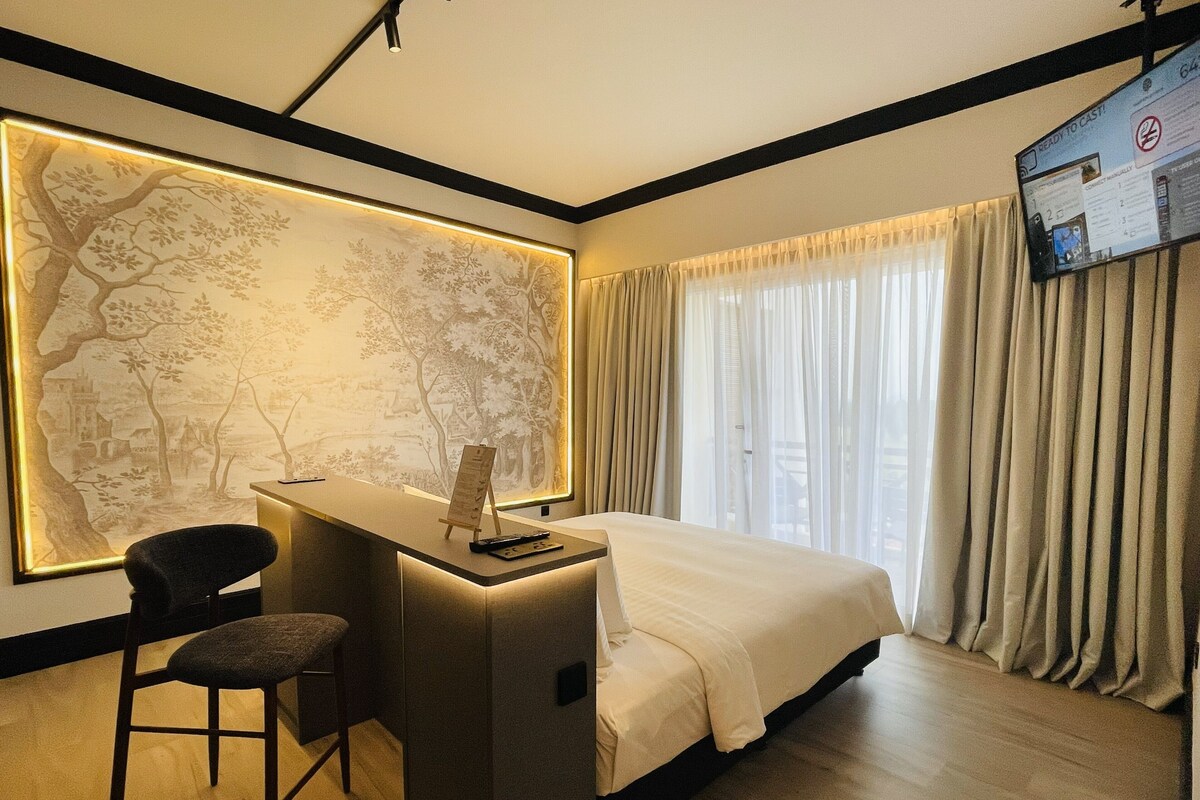 A hotel room with a desk, chair, bed, and a large wall mural.