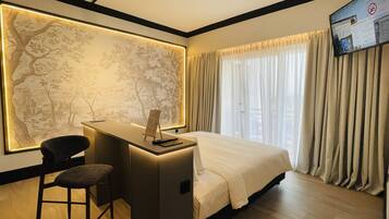 A hotel room with a desk, chair, bed, and a large wall mural.