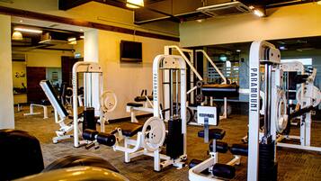 Un gimnasio con diversos equipos de ejercicio, incluyendo máquinas de pesas y aparatos de cardio.