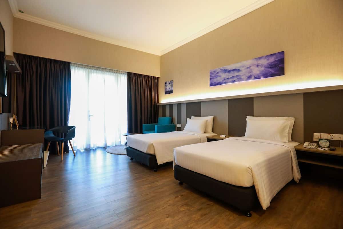 A hotel room with two beds, a desk, a chair, and a painting on the wall.