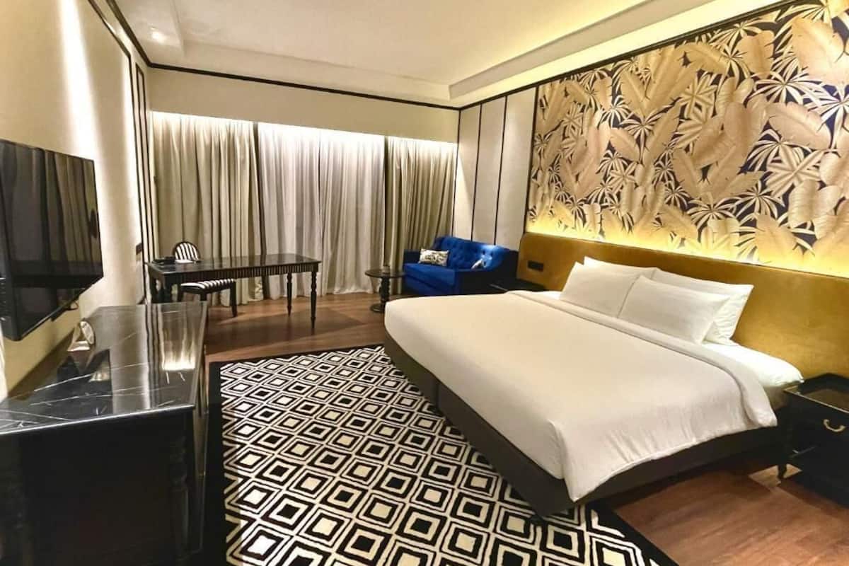 A modern hotel room with a large bed, a desk, and a television.