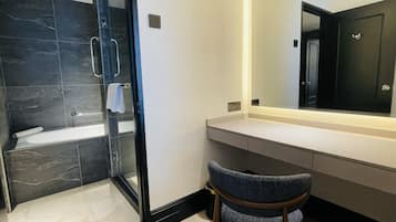 A modern bathroom with a glass shower enclosure, a white bathtub, and a vanity with a mirror.
