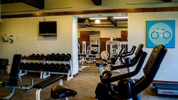 Un gimnasio equipado con varios aparatos de ejercicio, incluyendo mancuernas, bancos y máquinas de cardio.