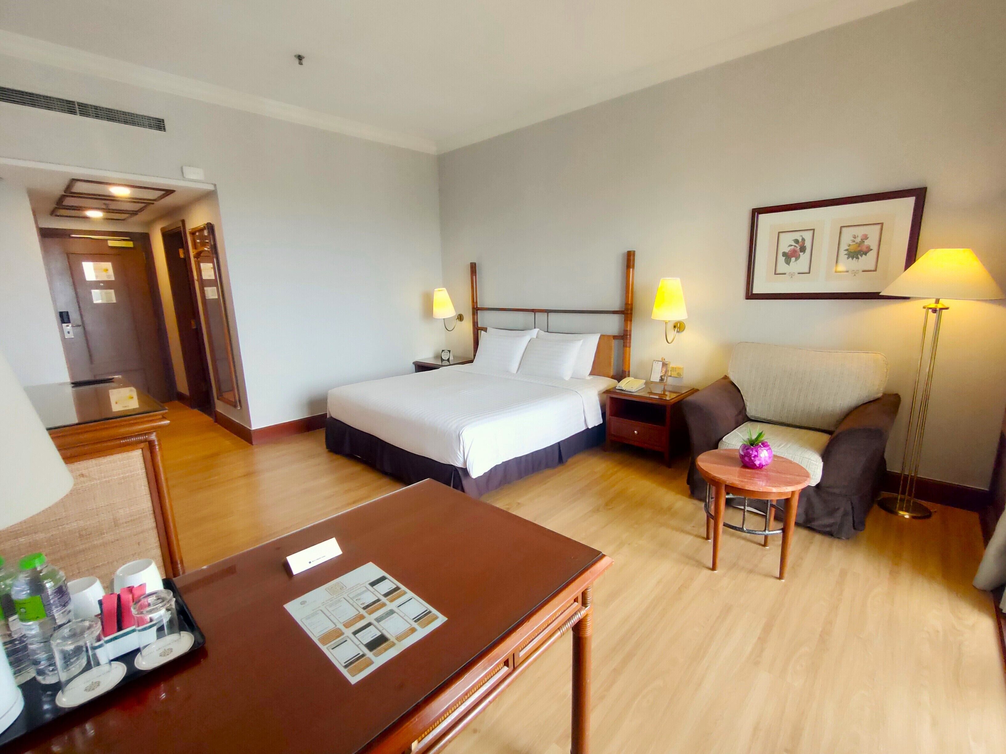 Une chambre d’hôtel comprenant un lit, un bureau, une chaise, un canapé et une table de chevet avec des lampes.