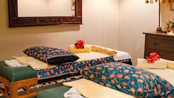 Two plush beds with floral-patterned bedding and ornate mirror create a classic retreat.