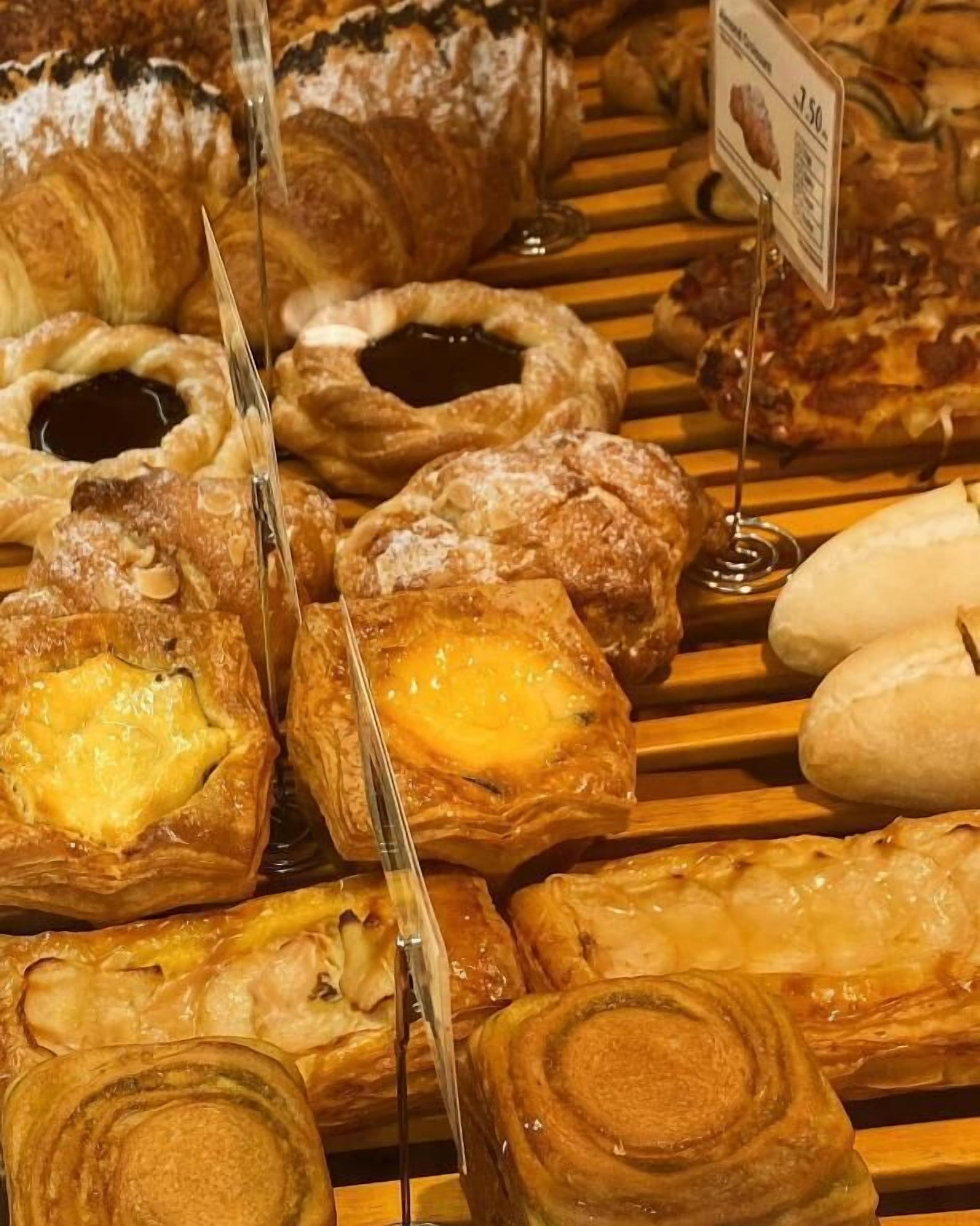 Variedad de pasteles expuestos sobre una superficie de madera, incluyendo tartas y pasteles con relleno visible.