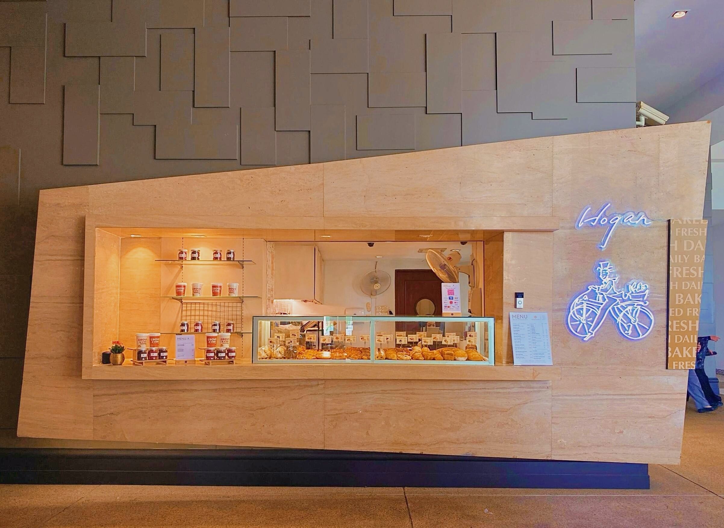 A bakery counter with a neon bicycle sign, a menu board, and various baked goods displayed in the window.