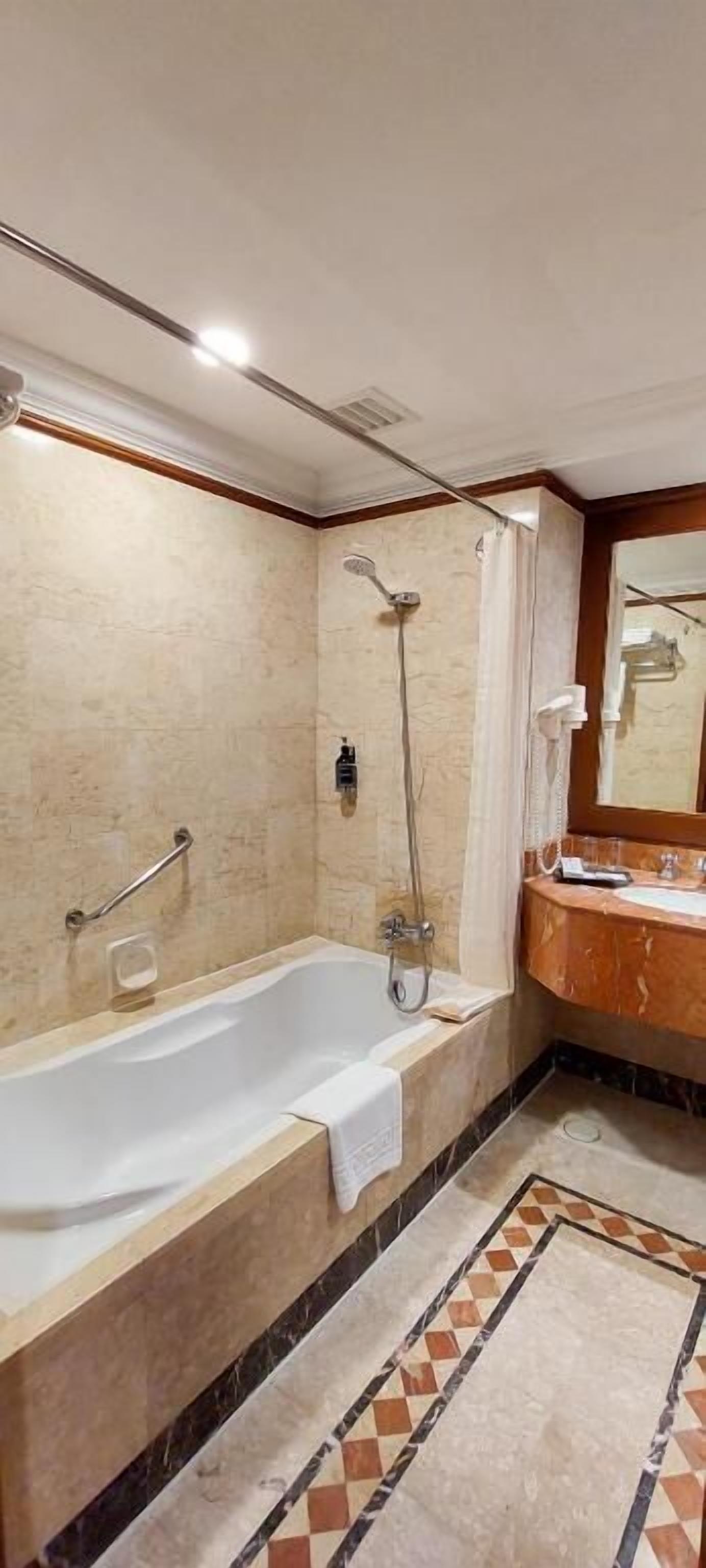 A bathroom with a bathtub, shower, and a vanity with a mirror.