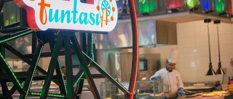 A Ferris wheel with a sign that reads "Funtasi" and a chef preparing food in the background.