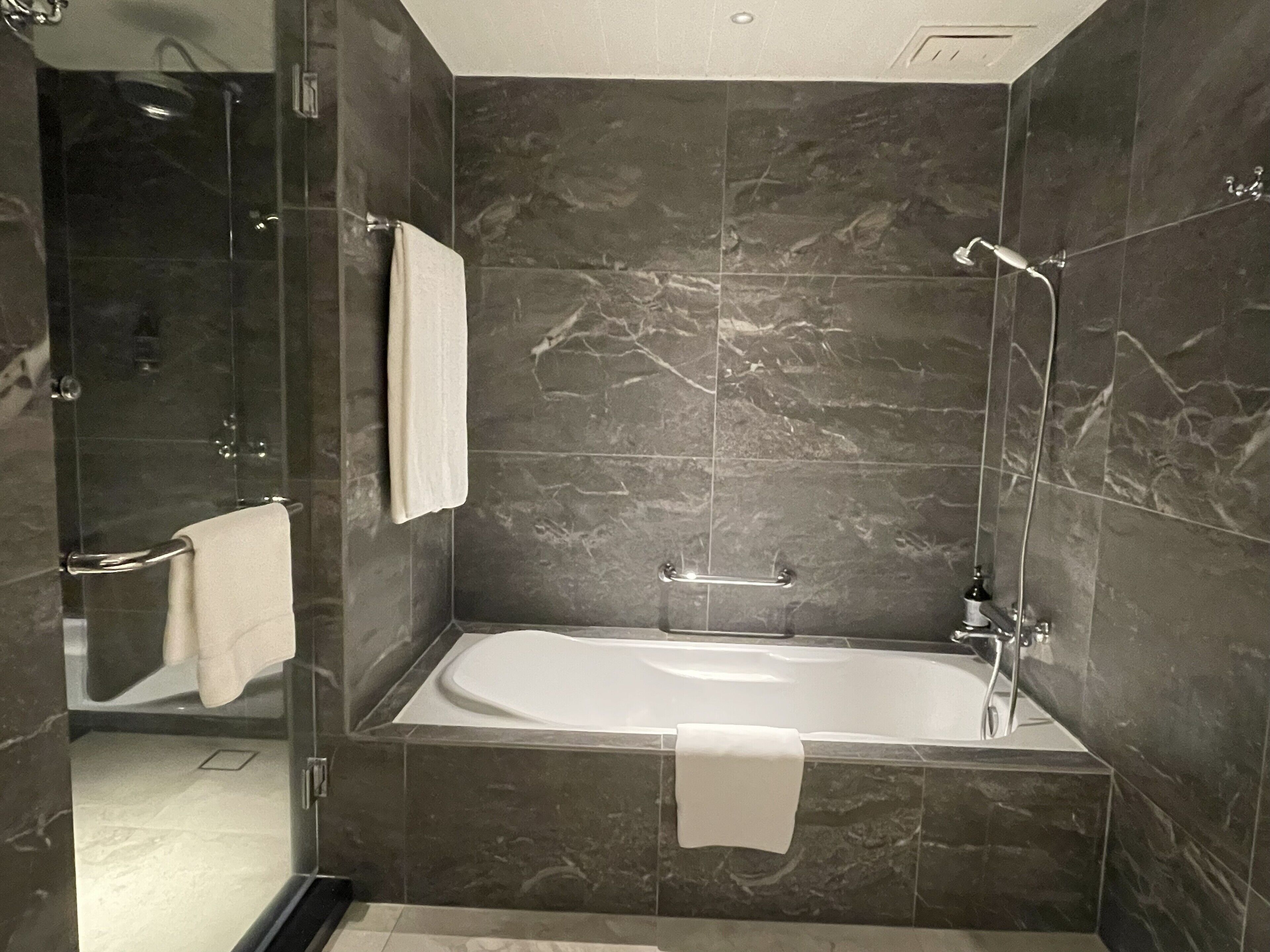 Un baño moderno con una bañera independiente, cabina de ducha de vidrio y paredes de mármol.