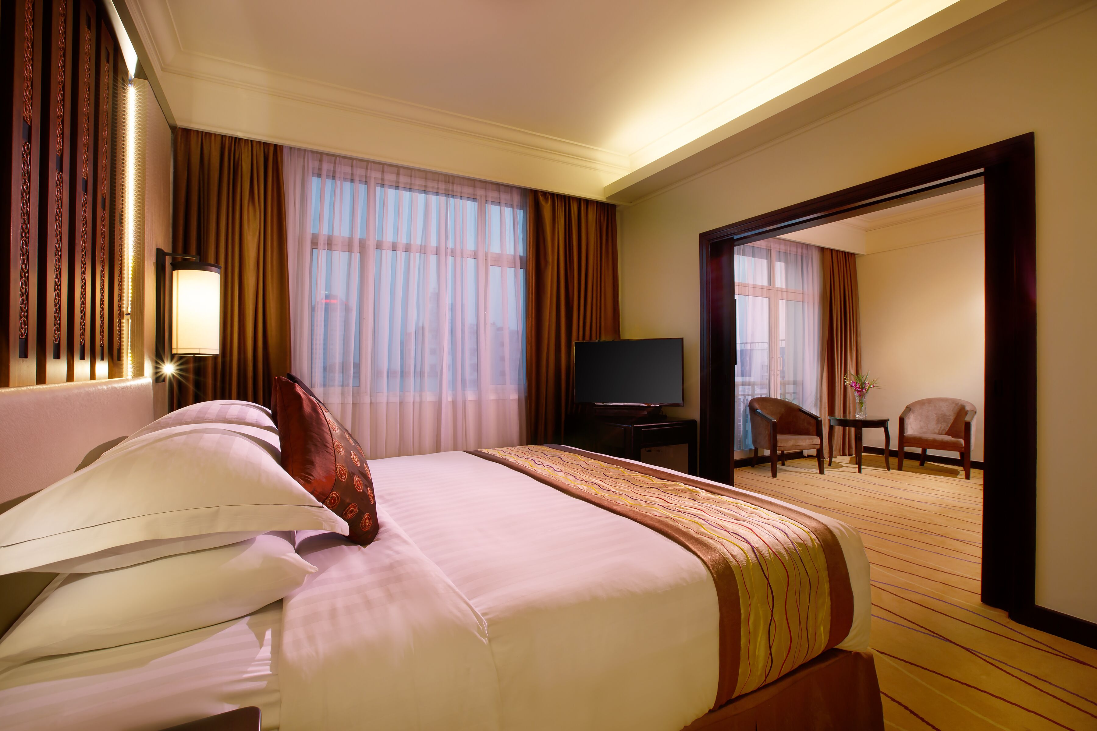 Una habitación de hotel con una cama grande, un televisor, un escritorio y dos sillas.