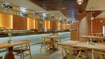 A modern restaurant with wooden furniture, a long counter, and decorative lighting.