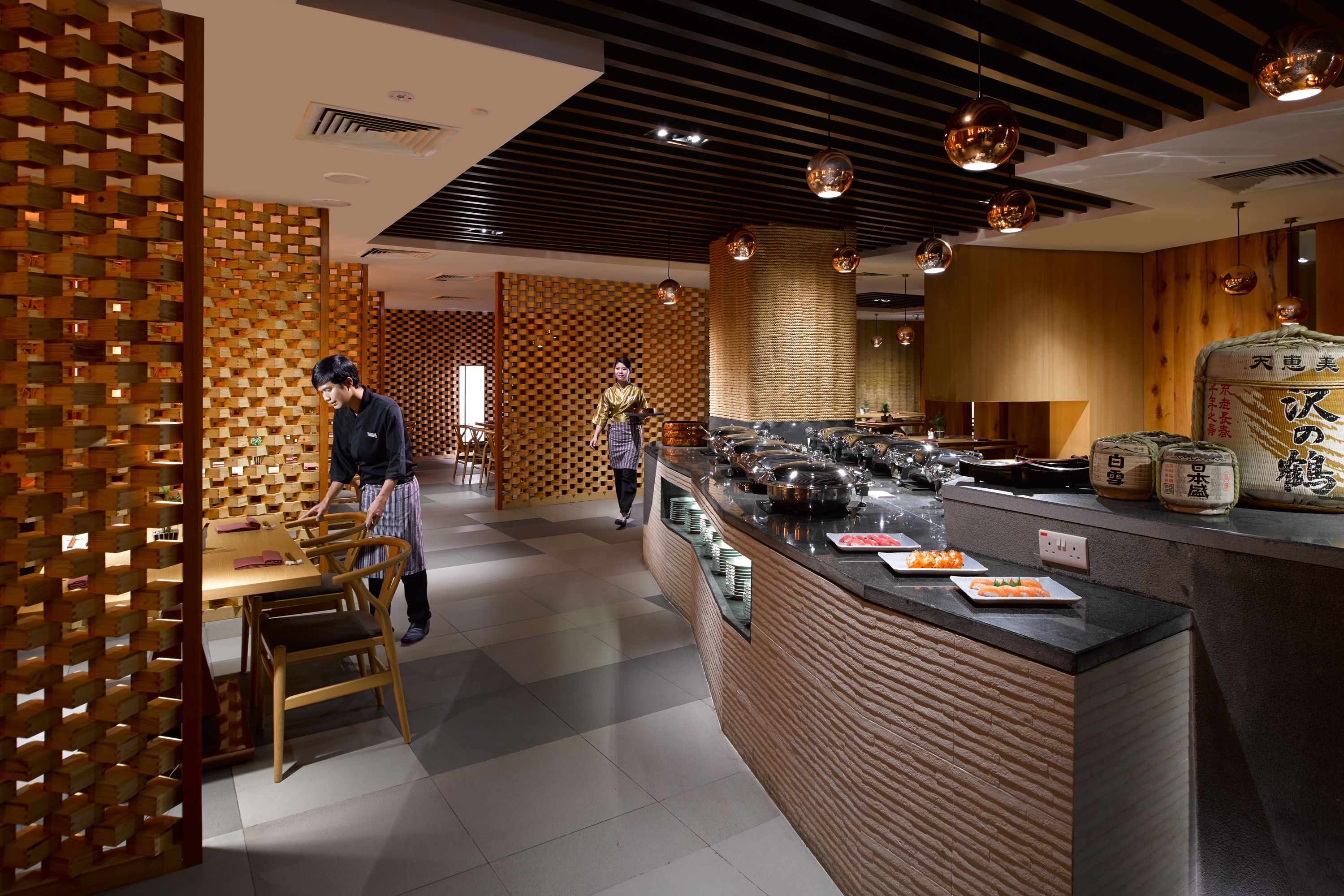 Ein Restaurantinnenraum mit einer Wandgestaltung aus Holz, einer Theke mit Speisen und einer Person, die sich dort bewegt.