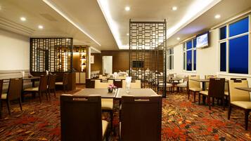 A hotel lobby with a seating area, tables, and a decorative screen.