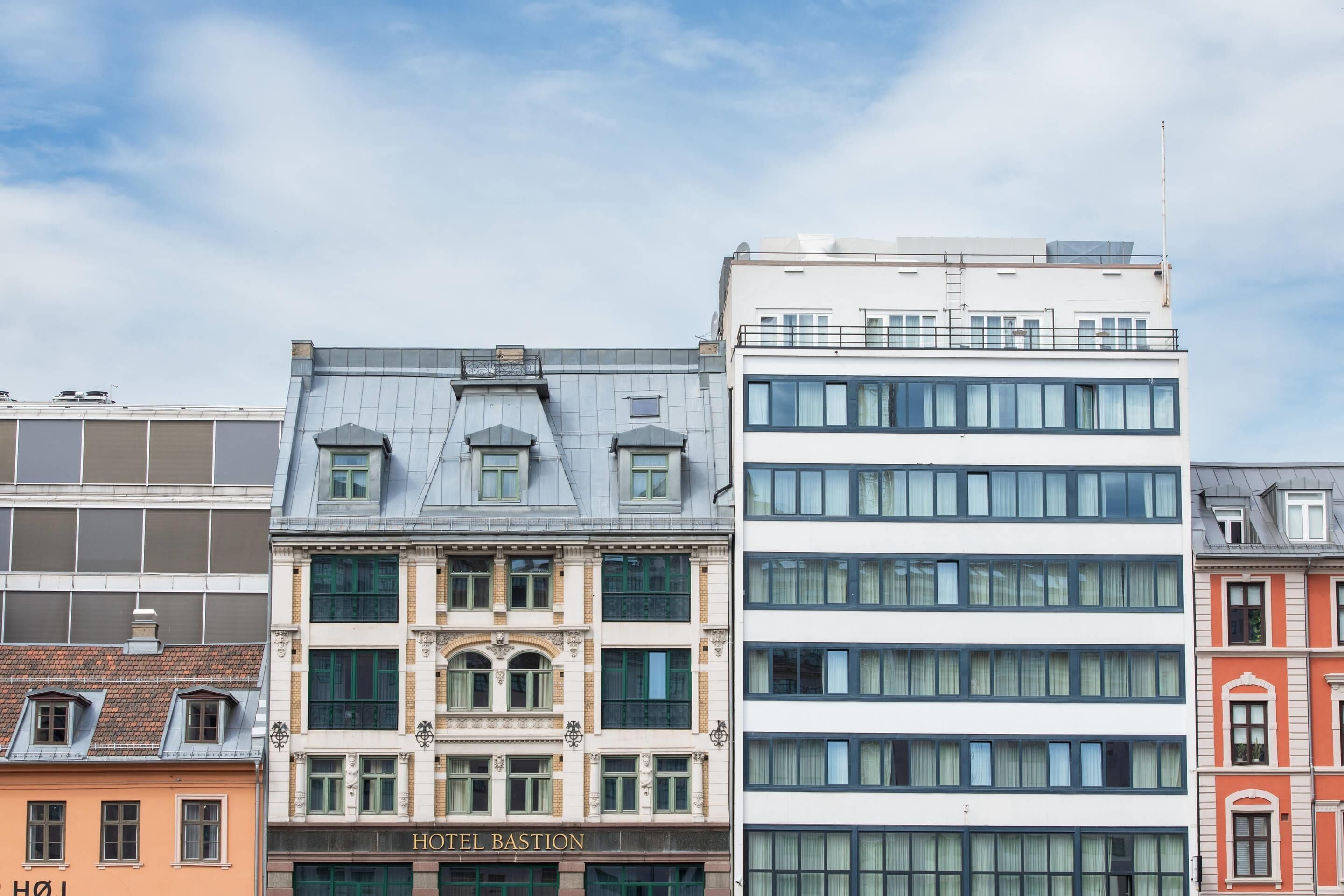 Un edificio de varios pisos con un llamativo letrero 'HOTEL BASTION', grandes ventanales y un techo plano.