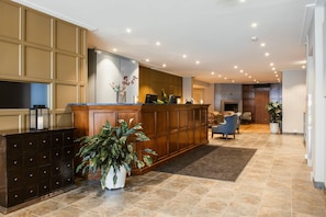 A spacious lobby with a reception desk, a large potted plant, and a seating area with chairs. - Home Hotel Bastion (Oslo)