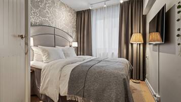 A modern bedroom with a large bed, a patterned wall, and a TV mounted on the wall.