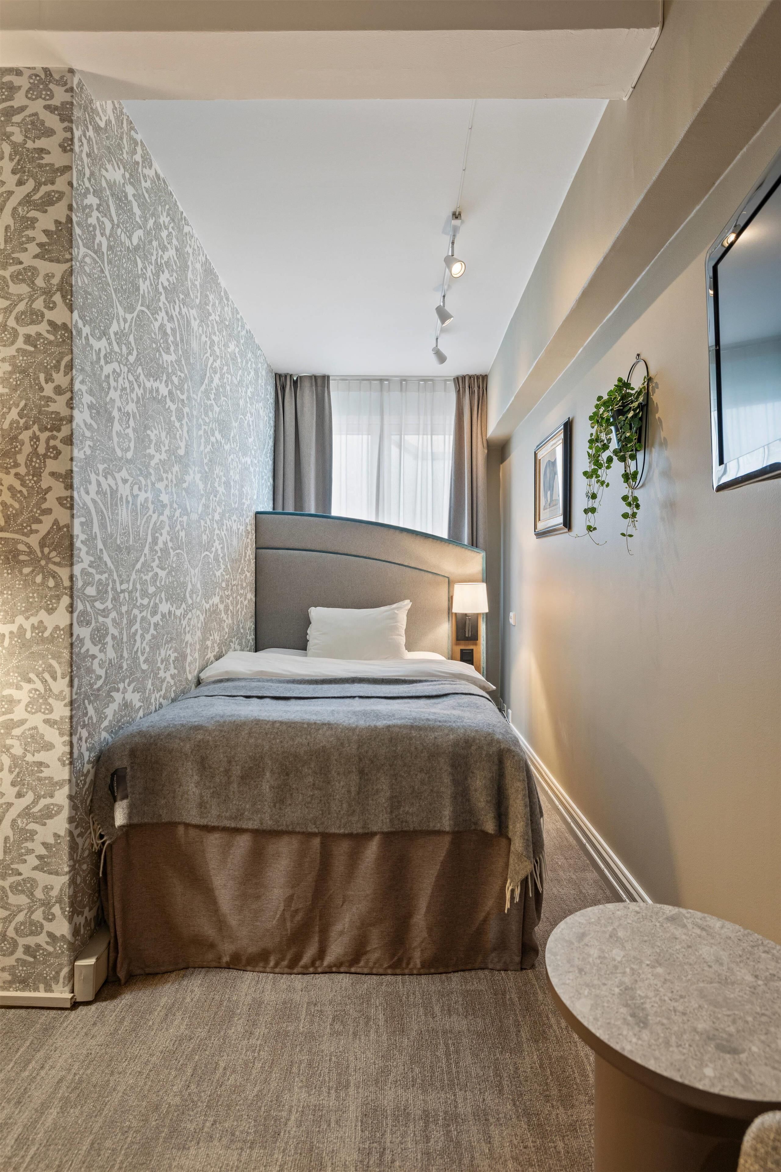 A hotel room with a bed, bedside table, and a small round table.