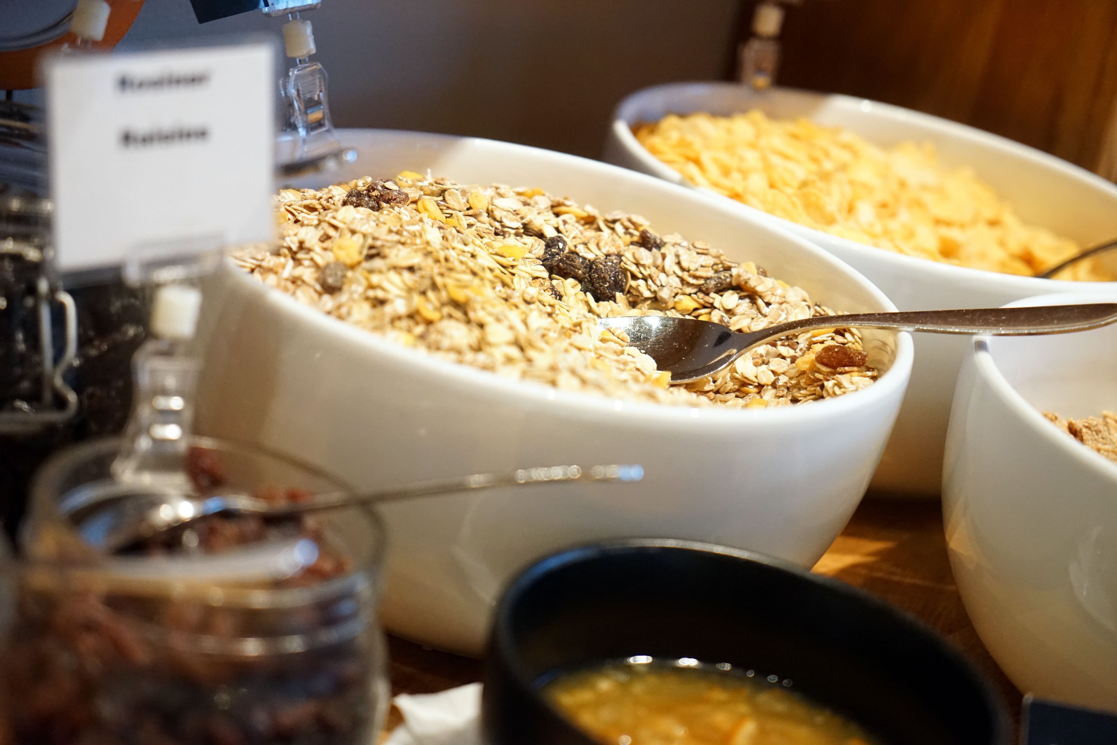 A buffet with various dishes including oatmeal, fruits, and nuts.