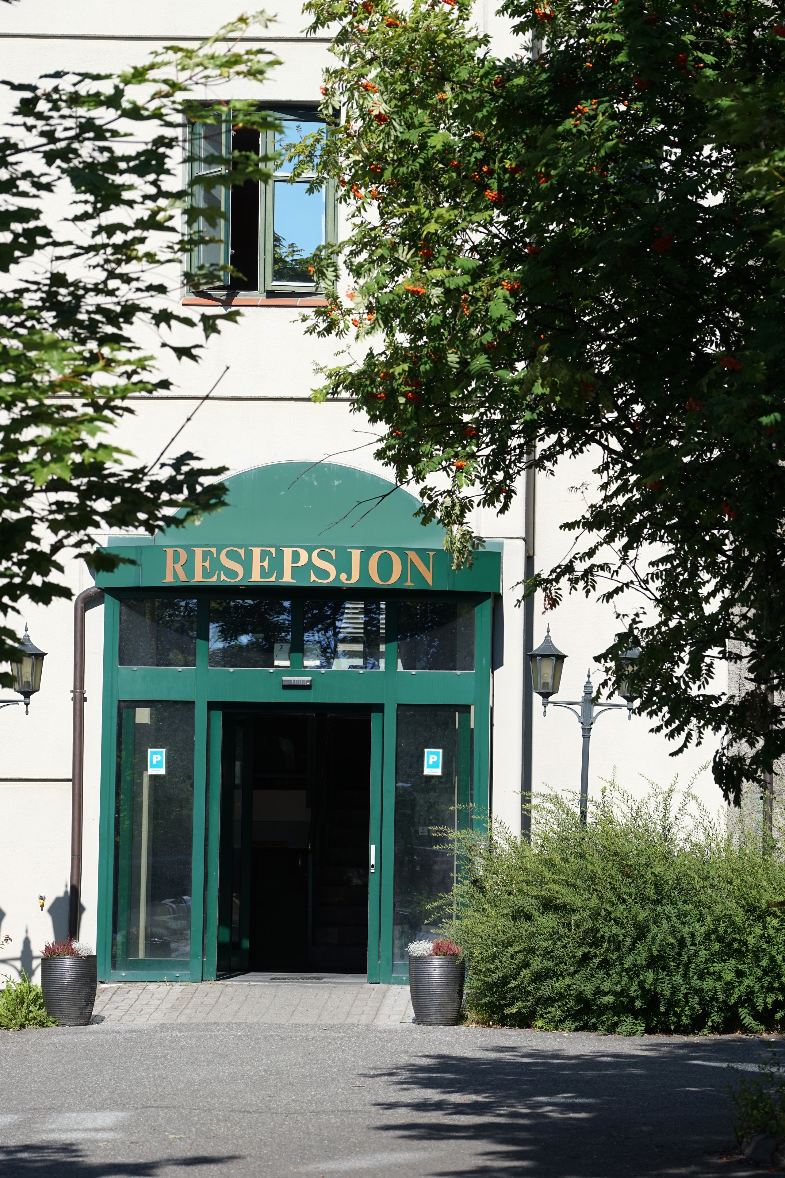 En byggnad med en grön entré där det står ”RECEPTION”.