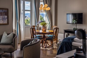 Una habitación bien iluminada con una mesa de comedor, sillas, un televisor y una ventana con cortinas.
