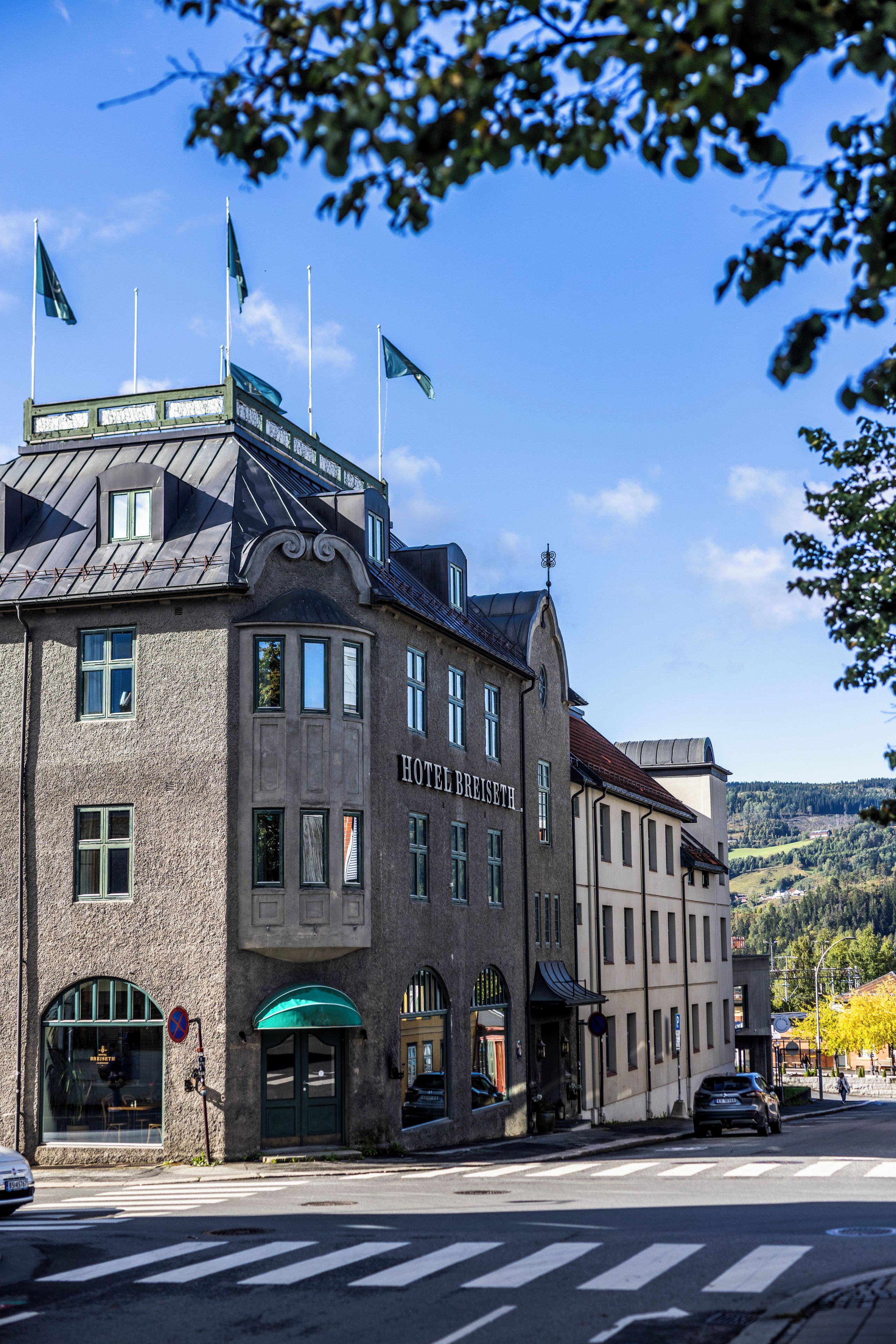 A hotel with a classic architectural style, featuring a prominent entrance with a green awning and multiple flags.