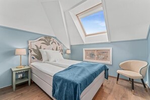 A bedroom with a bed, a nightstand, a chair, a window, and a picture frame on the wall. - Hotel Breiseth (Lillehammer)