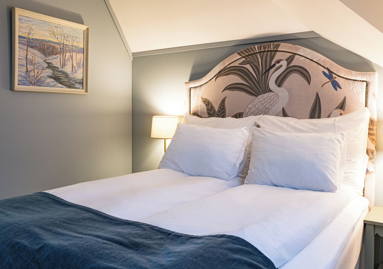A neatly made bed with white linens and a dark blue throw blanket.
