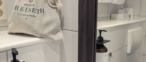 A bathroom with a white sink, a mirror, a towel hanging on the wall, and a bottle of hand soap.