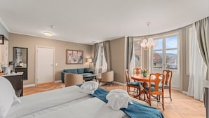 A hotel room with a bed, a sofa, a dining table with chairs, a mirror, and a painting on the wall. - Hotel Breiseth (Lillehammer)