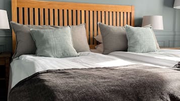 A neatly made bed with a wooden headboard, grey pillows, and a grey throw blanket.