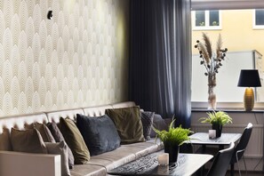 A modern living room with a sofa, a dining table with chairs, and a window with curtains. - BEST WESTERN Princess Hotel (Norrköping)