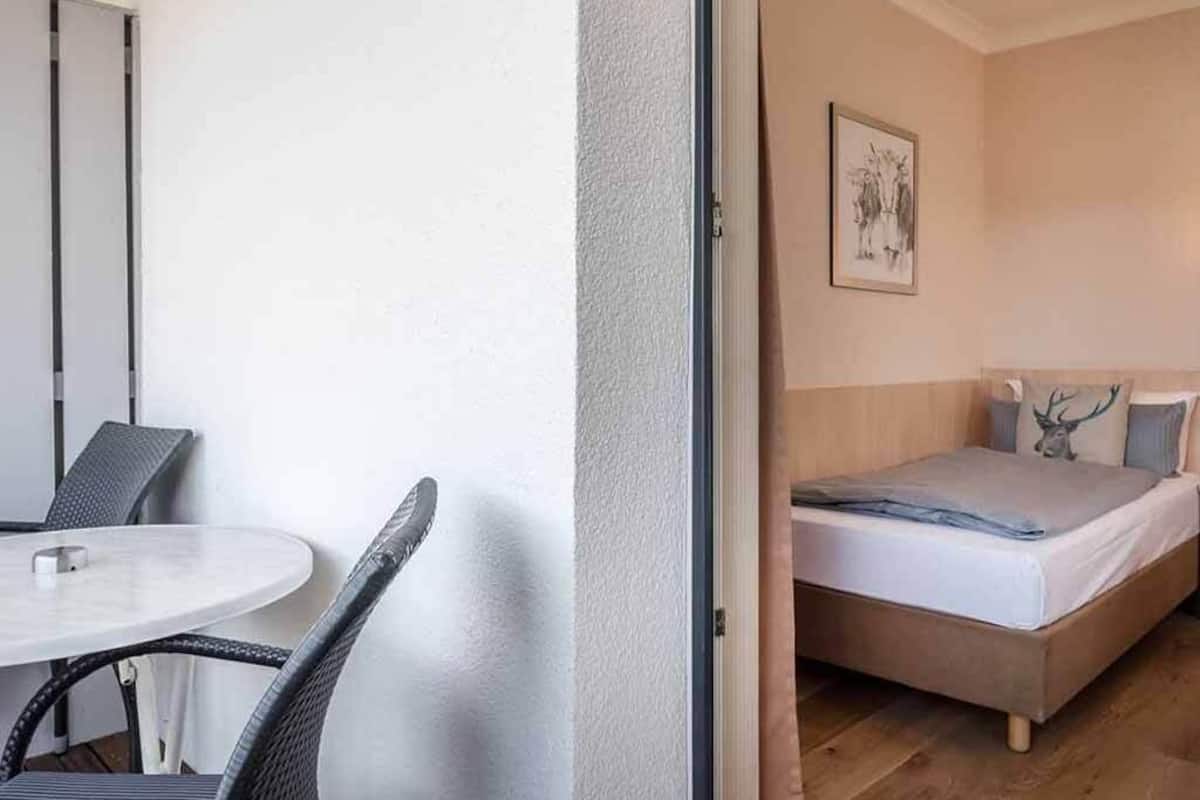 Een kleine, moderne kamer met een bed, een ronde tafel en een stoel.