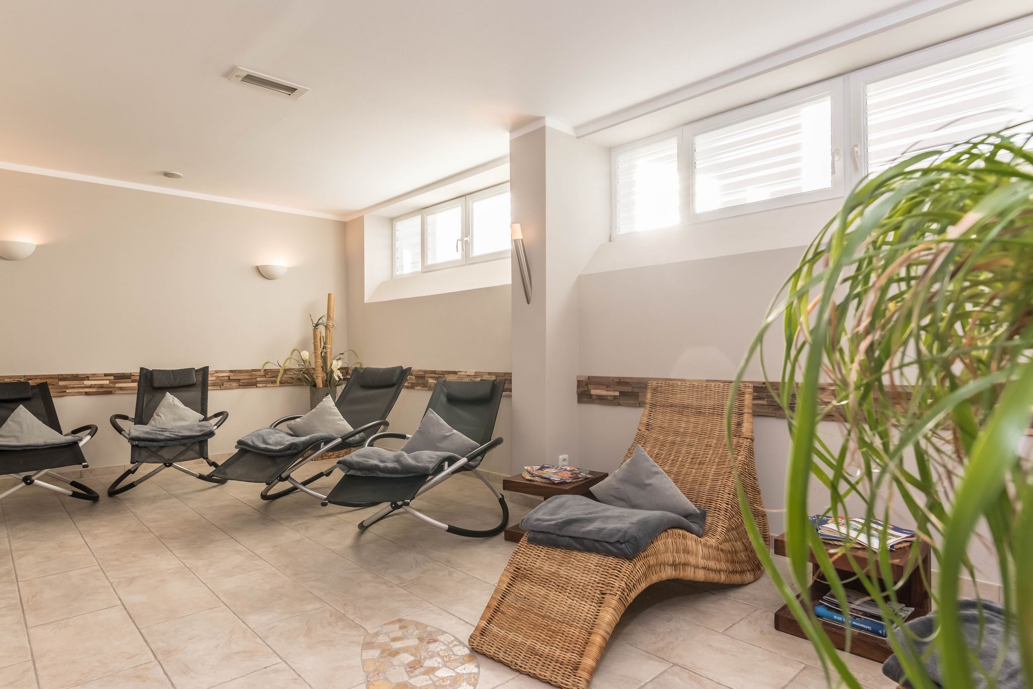 Un cuarto de spa con sillones reclinables, una silla lounge de mimbre y una mesita con libros.