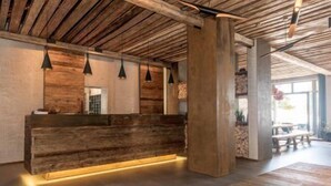 Un área de recepción con un mostrador de madera, iluminación colgante y una pared de piedra.