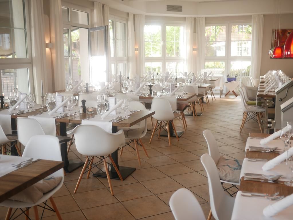 Un vaste espace dédié à la salle à manger, avec de nombreuses tables et chaises, de grandes fenêtres et un aménagement intérieur moderne.