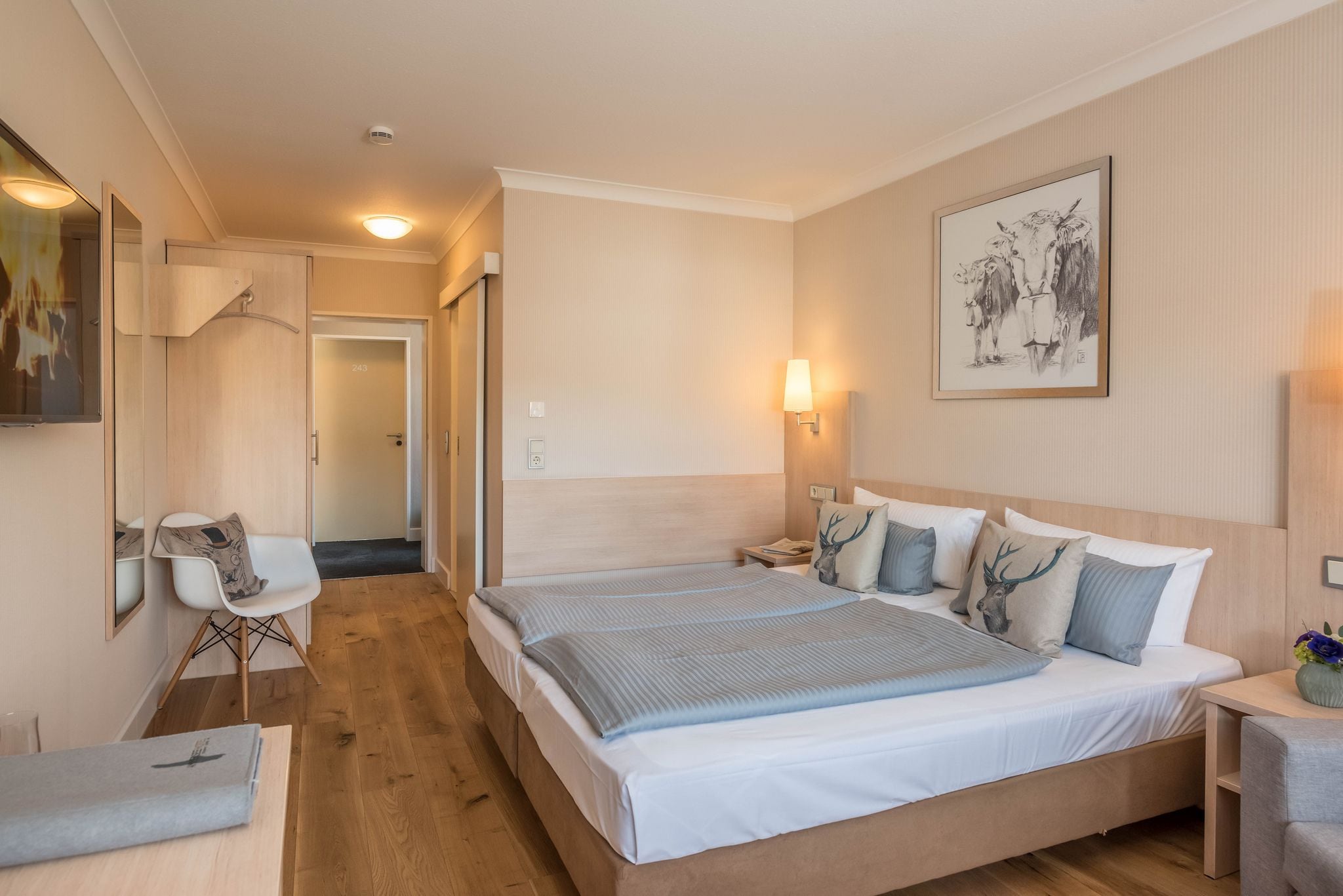A modern hotel room with a large bed, bedside tables, a desk, and a chair.