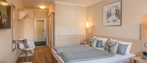 A modern hotel room with a large bed, bedside tables, a desk, and a chair.