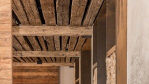 Un interior moderno con vigas de madera a la vista, una silla blanca, una silla negra y una pequeña mesa con una planta.