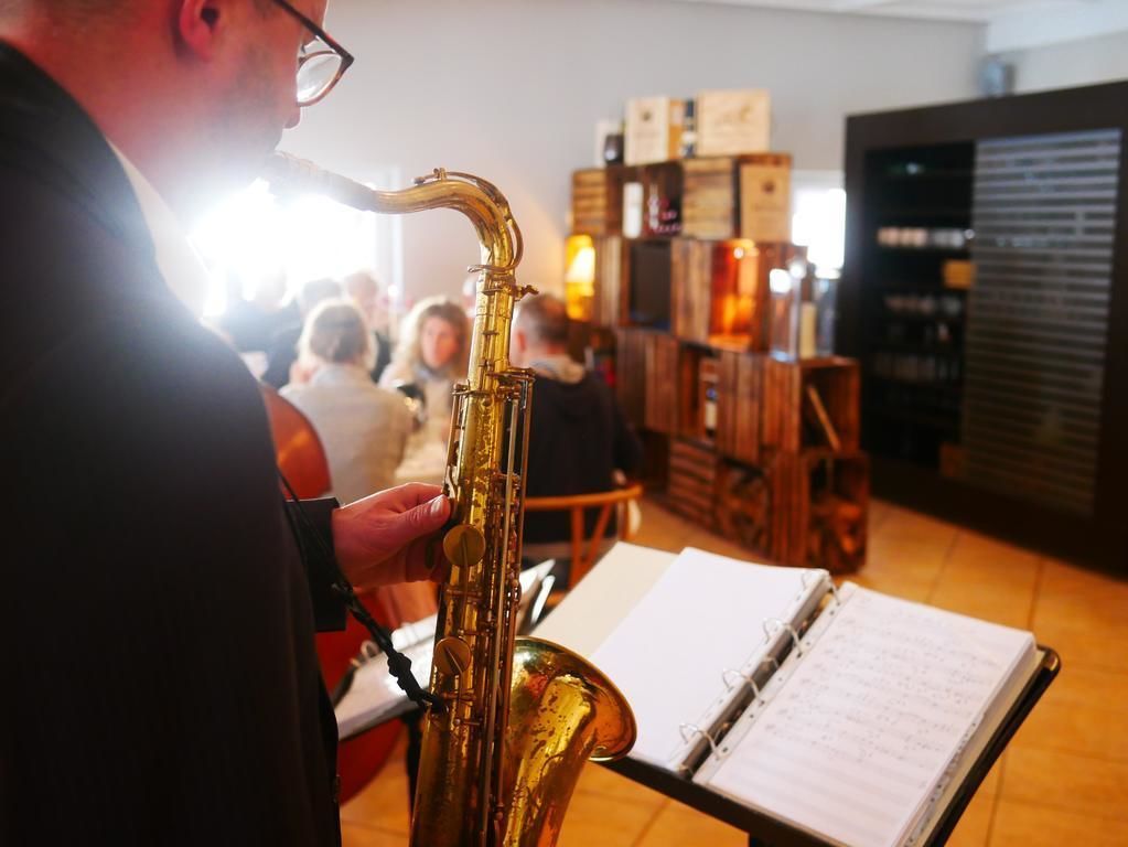 A person playing a saxophone in a room with a music stand and sheet music.