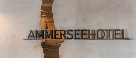 A wall with a large, metallic sign reading "AMMERSEEEHOTEL" in a bold, sans-serif font.