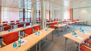 A conference room with multiple tables and chairs, equipped with water bottles and name cards.