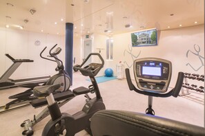 A gym with cardio machines, a digital display, and a wall-mounted television. - Best Western Plus Hotel Fellbach-Stuttgart (Fellbach)