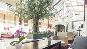 A spacious lobby with a large tree, comfortable seating, and a modern design. - Best Western Plus Hotel Fellbach-Stuttgart (Fellbach)