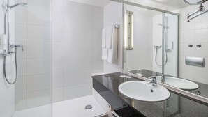 Une salle de bain moderne dotée d’une douche à parois de verre, de deux lavabos et d’un grand miroir.