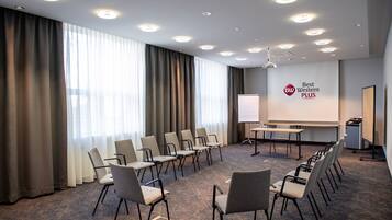 Een vergaderzaal met een projectorscherm, een whiteboard en een logo op de muur.