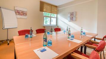A conference room with a long table, red chairs, and water bottles.