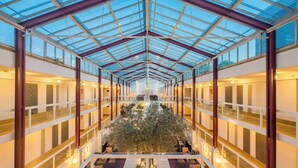 A spacious atrium with a glass ceiling, a central tree, and multiple levels with seating areas. - Best Western Plus Hotel Fellbach-Stuttgart (Fellbach)